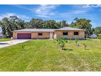 Charming brick home featuring an attached garage, lush lawn, and mature trees at 3380 Blossom St, Kissimmee, FL 34746