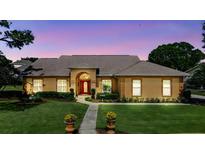 Charming exterior view of a single-story home with a red front door and well-manicured landscaping at 34021 Park Ln, Leesburg, FL 34788
