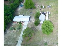 An aerial view of a cozy home with a long driveway and spacious yard, nestled among lush trees at 37149 Grays Airport, Lady Lake, FL 32159