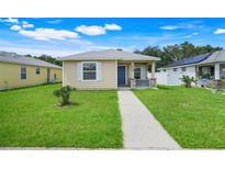 Charming single-story home featuring a blue front door, a cozy porch, and a well-maintained lawn at 4649 College Dr, Orlando, FL 32811