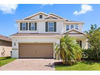 Two-story home featuring a two-car garage, brick-paved driveway, well-manicured lawn, and neutral-toned exterior paint with green shutters at 4869 Grassendale Ter, Sanford, FL 32771