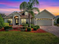 Charming single-story home with a well-manicured lawn and a paver driveway leading to a two-car garage at 4976 Sandpiper Dr, Oxford, FL 34484