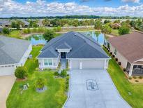Stunning aerial view of home with pond, manicured lawn, and three-car garage in a well-maintained community at 5905 Caulk Ct, The Villages, FL 32163