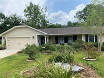 Charming home featuring a well-maintained lawn, a variety of plants, and a one-car garage at 66 Elmwood Trl, Deland, FL 32724
