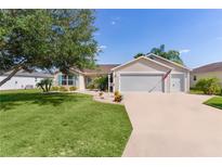 Charming single-story home with a well-manicured lawn, mature tree, and two-car garage at 898 Abaco Path, The Villages, FL 32163