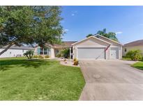 Charming single-story home featuring a well-manicured lawn, mature tree, and attached two-car garage at 898 Abaco Path, The Villages, FL 32163