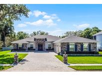 Stunning single-story home featuring stacked stone accents and a spacious brick driveway at 9518 Mid Summer Ln, Leesburg, FL 34788