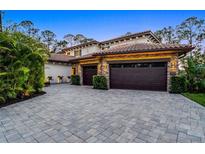 Stately home featuring stone accents, a tile roof, and a spacious driveway with a three-car garage at 10122 Royal Island Ct, Orlando, FL 32836