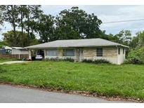 Charming single-story home featuring a covered car port, neutral brick accents, and mature trees at 1022 E 3Rd Ave, Mount Dora, FL 32757