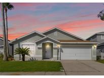Charming single-story home with a well-manicured lawn, attached garage and tropical landscaping at 157 Julliard Blvd, Davenport, FL 33897