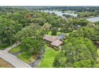 Aerial view of an estate home surrounded by lush landscaping with a private pool near a lake at 1930 Country Club Rd, Eustis, FL 32726