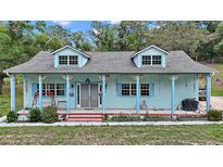 Charming home with dormer windows, front porch with decorated pillars and a light blue exterior at 19703 Lake Lincoln Ln, Eustis, FL 32736