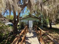 Quaint home with a wooden walkway, surrounded by trees draped with Spanish moss at 2001 Bates Ave, Eustis, FL 32726