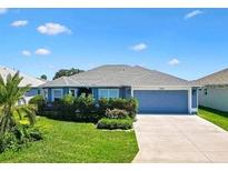 Charming single-story home featuring a two-car garage and well-manicured front lawn under a blue sky at 2160 Biller Cir, The Villages, FL 32163