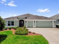 Charming single-story home featuring a well-manicured lawn, three-car garage, and inviting front entrance at 2568 Jupiter Way, The Villages, FL 32163