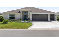 Charming home featuring a well-manicured lawn, a two-car garage, and decorative front door with a wreath at 2988 Sentell St, The Villages, FL 32163