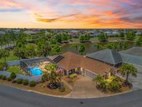 Aerial view showcases a beautiful home with a screened pool, lush landscaping, and a tranquil pond backdrop at 2998 Kramer Ct, The Villages, FL 32163