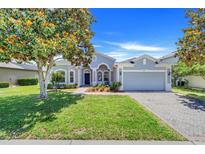 Charming one-story home featuring a well-manicured lawn, mature tree, and a two-car garage on a sunny day at 4716 Block Island Ln, Clermont, FL 34714
