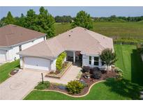 Charming single-story home with a two-car garage, beautifully landscaped front yard and a serene waterfront view at 541 Carrera Dr, The Villages, FL 32159