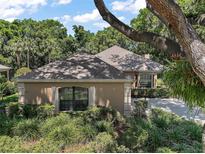 Tan home with landscaped front yard and mature shade trees giving a verdant surrounding to the property at 621 High Point Dr, Mount Dora, FL 32757