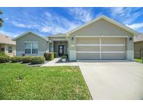 Charming single-story home featuring a manicured lawn, two-car garage, and inviting front entrance at 8652 Se 133Rd Ln, Summerfield, FL 34491