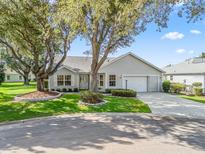 Charming single story home featuring mature trees, landscaped yard, paved driveway and attached two car garage at 8980 Se 178Th Muirfield Pl, The Villages, FL 32162