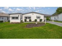 Charming single-story home with a well-manicured lawn and tidy landscaping at 1146 W Boone Ct, Lady Lake, FL 32159