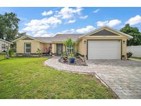 Charming one-story home featuring a manicured lawn, beautiful landscaping, and paved driveway at 1204 Monterey Dr, Eustis, FL 32726