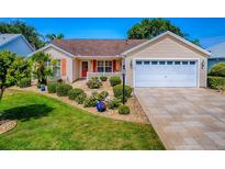 Charming single-story home featuring a well-manicured lawn, tasteful landscaping, and a two-car garage at 1206 Thompson Ave, The Villages, FL 32162