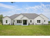 Modern farmhouse exterior showcasing a well-manicured lawn and black trimmed windows and doors at 12565 Cynthia Ln, Clermont, FL 34715