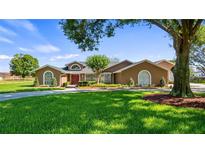 Charming single-story home with a well-manicured lawn, mature trees, and a welcoming red front door at 15245 Arabian Way, Montverde, FL 34756