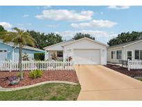 Charming single-story home with a white picket fence, lush landscaping, and a well-maintained front yard at 1728 Morelos Rd, The Villages, FL 32159