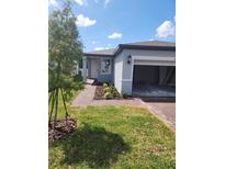 Charming single-Gathering home featuring a well-maintained lawn, brick driveway, and attached two-car garage at 1808 Carnostie Rd, Winter Haven, FL 33884