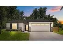 Charming home featuring stone accents, lush lawn, and a modern design on a sunny day at 201 Hillside Ave, Umatilla, FL 32784