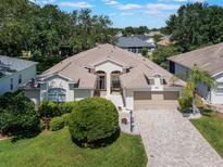 Inviting one-story home with a manicured lawn, brick driveway, and mature landscaping, perfect for curb appeal at 25243 River Crest Dr, Leesburg, FL 34748