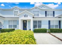 Charming townhome with light blue exterior, dark blue shutters, and manicured landscaping at 2530 Maneshaw Ln, Kissimmee, FL 34747