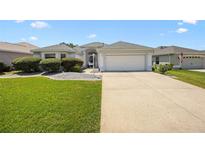 Charming single-story home featuring a well-manicured lawn, paved driveway, and a two-car garage at 3008 Bridgefield Ct, The Villages, FL 32162