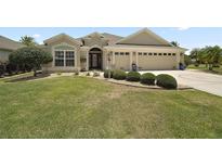 Charming single-story home featuring a well-manicured lawn, mature landscaping, and a two-car garage at 3411 Eisenhower Way, The Villages, FL 32163