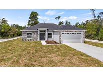 Charming single-story home featuring stone accents, a two-car garage, and a well-manicured lawn at 40685 E Ninth Ave, Umatilla, FL 32784