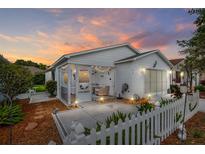 Charming home featuring a screened porch with decorative lighting and a well-maintained yard at sunset at 412 Hildalgo Dr, The Villages, FL 32159