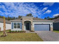 Charming single-story home featuring stone accents, a two-car garage, and beautifully landscaped front yard at 5037 Balsam Falls Rd, Deland, FL 32724