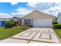 Charming single-story home with well-maintained landscaping and decorative driveway at 735 Palma Dr, Lady Lake, FL 32159