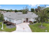 Charming single-story home with a well-manicured lawn, decorative driveway, and mature landscaping at 8608 Se 141St Street Rd, Summerfield, FL 34491