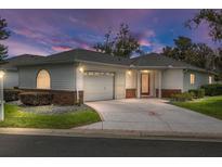 Charming home featuring a well-manicured lawn, attached garage, and an inviting red front door at 8608 Se 141St Street Rd, Summerfield, FL 34491