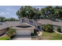 Charming home featuring a two-car garage, a well-manicured lawn, and mature trees offering plenty of shade at 8705 Village Green Blvd, Clermont, FL 34711