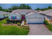 Charming single-story home with a well-manicured lawn, beautiful landscaping, and a brick-paved driveway at 1016 Eagles Lndg, Leesburg, FL 34748