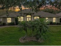Charming single-story home featuring a well-manicured lawn and arched entryway, bathed in the warm glow of dusk at 11036 Bronson Rd, Clermont, FL 34711