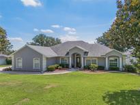 Charming single-story home featuring manicured landscaping, a circular driveway, and a welcoming entrance with stately columns at 11437 Alameda Sandra Dr, Clermont, FL 34711