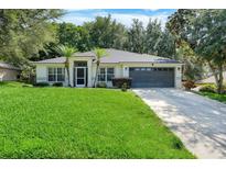 Charming single-story home featuring a lush green lawn and a two-car garage at 1311 Rain Forest Ln, Minneola, FL 34715