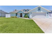 Charming single-Gathering home with light blue exterior paint, well-manicured lawn, and a two-car garage at 15022 Se 94Th Ct, Summerfield, FL 34491
